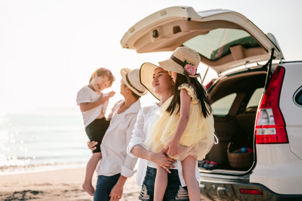 Happy asian family on a road trip in their car. Dad, mom and daughter are traveling by the sea.